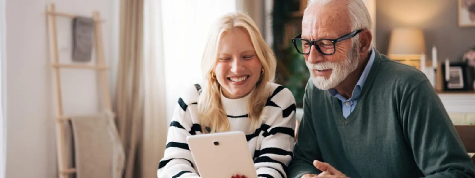 Granddaughter and grandfather using tablet computer to video call loved ones.