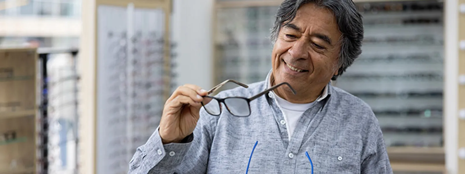 Senior man trying on glasses at the opticians shop.